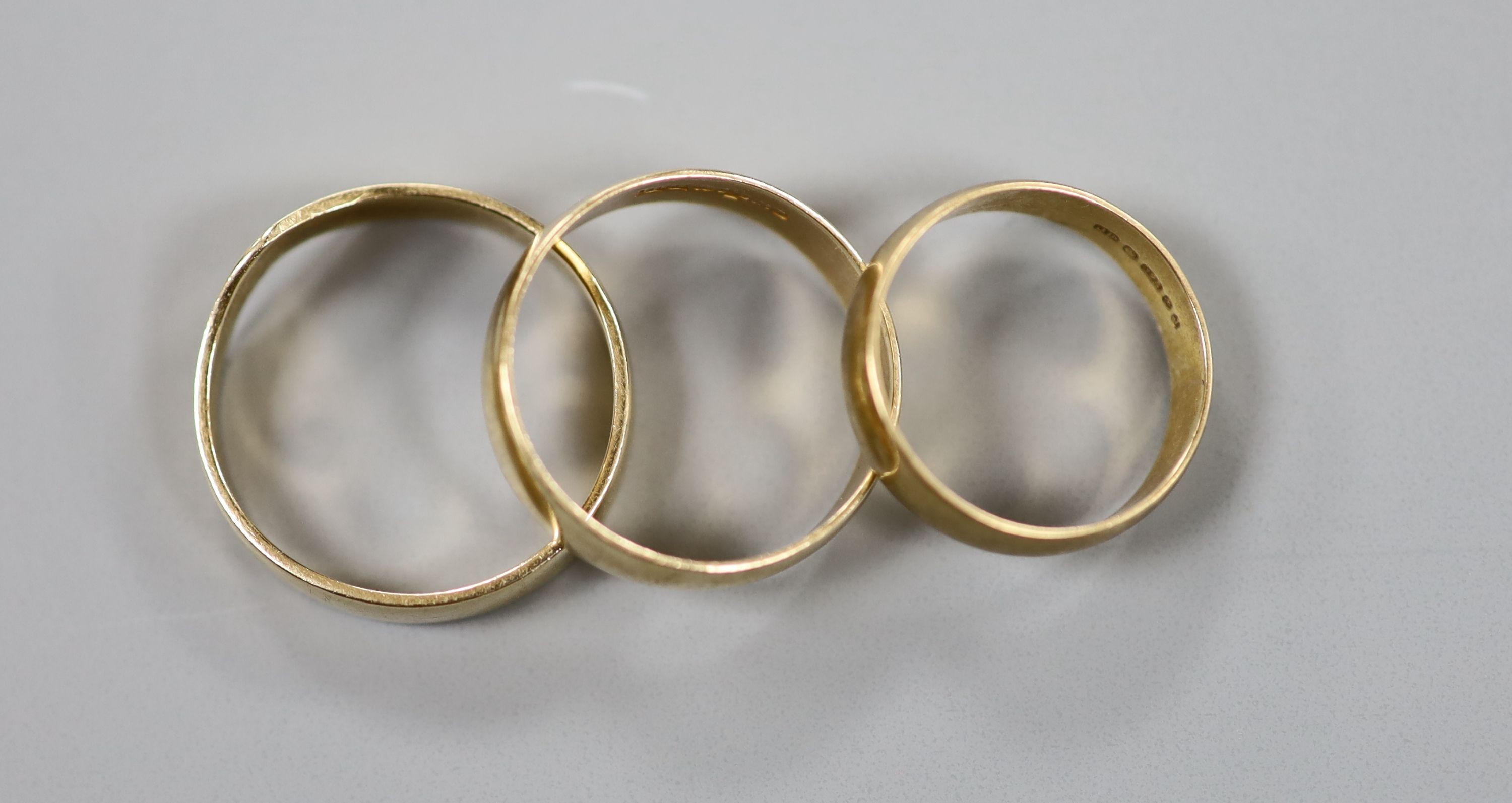 Two 9ct gold wedding bands, 4.7 grams and one other shaped yellow metal band, 3.3 grams.